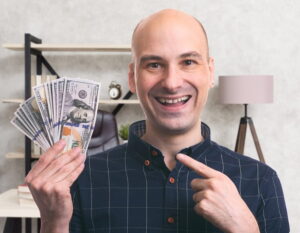 a male blogger holding $1000 in hand which he made from blogging