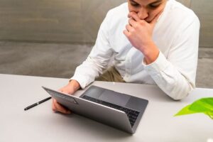 a man blogger is thinking deep to brainstorm blog post ideas in front of laptop and a pen next to it