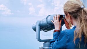 woman blogger using telescope to find the right position of a ship far away in the sea