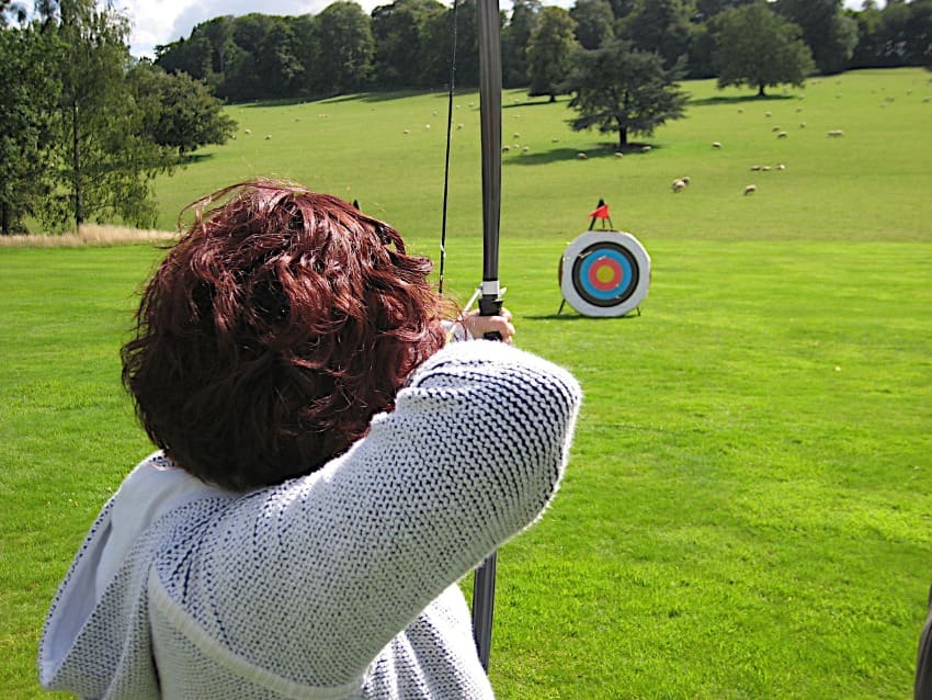 a woman blogger is focusing on her target outdoor on green archer lawn