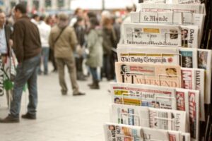 newspaper rack with few kind of newspapers that have a good headlines