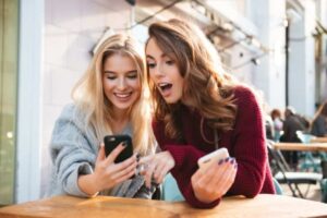 two best friends looking information on a user friendly site through a smartphones