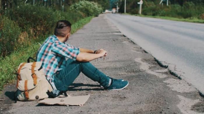 a male blogger sitting by the road side that has no cars and no traffic